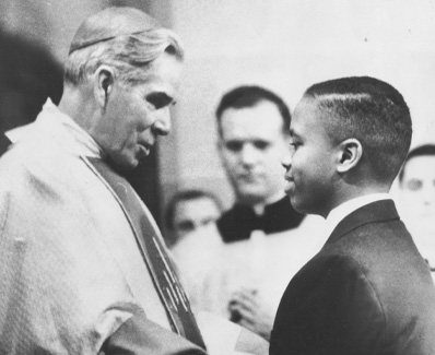 Archbishop Fulton J. Sheen speaking with a young man at a public gathering