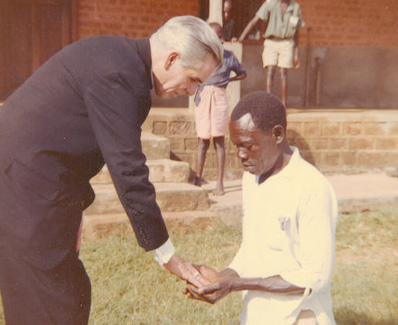 Archbishop Fulton J. Sheen placing his hand on a man’s hands during a missionary visit
